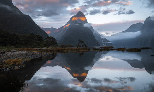 istock First sunrays lighting the peak of mountain with beautiful reflection in water surface in front of it 1253684994