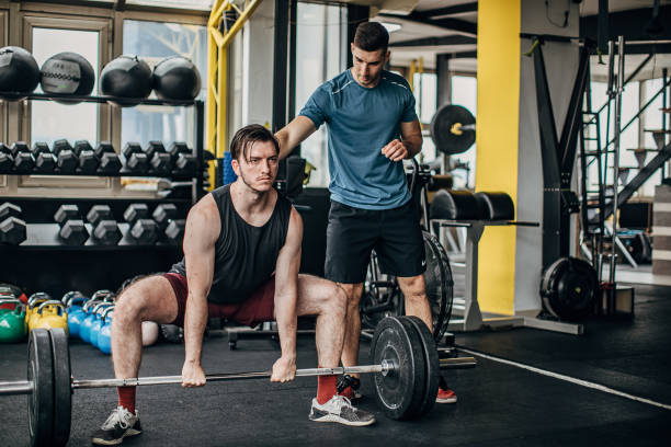 istock Determined man exercising in the gym with personal trainer 1253686192