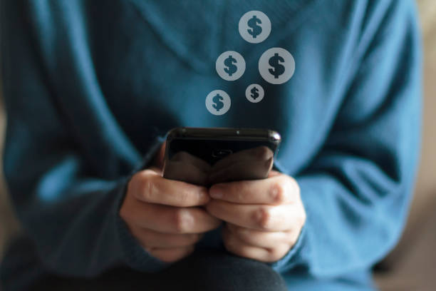 istock Woman holding smartphone with dollar icon 1253686876