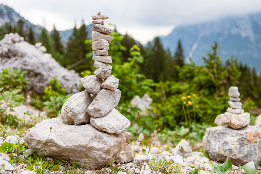 Close-up of stones and pebbles carefully arranged into balancing stacks among a mountain landscape.