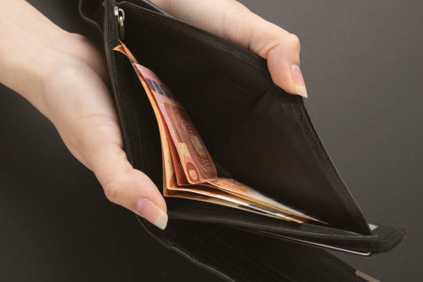 istock Female hands hold a wallet with cash on a black background 1253688566