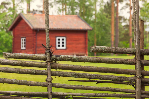 A traditional roundpole fence outside a small cottage or outhouse on the countryside in Svärdsjö, Dalarna, Sweden.