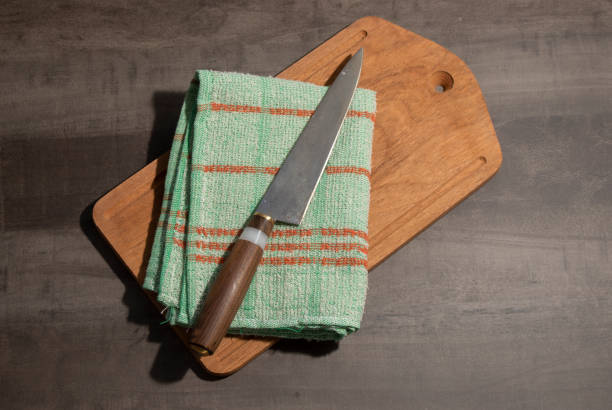istock Big kitchen knife with wood and handle handle lying on an old cutting board 1253691244