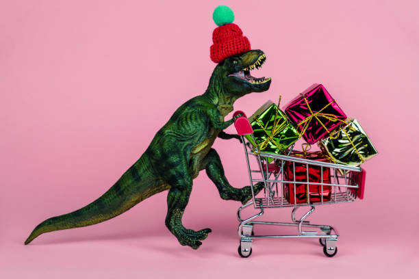 istock funny plastic toy dinosaur wearing tiny knitted hat and driving shopping trolley 1253691604