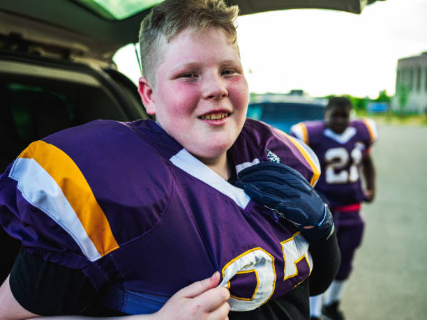 Junior Football player getting ready Blonde Junior Football player getting ready for practice at the outdoor field. overweight boy stock pictures, royalty-free photos & images