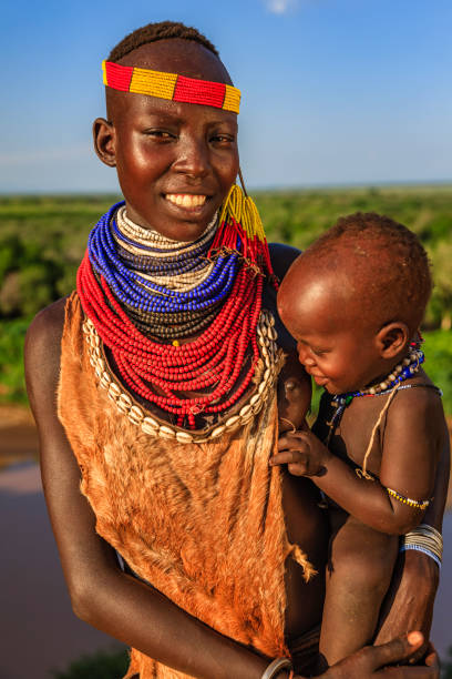 Woman from Karo tribe carrying her baby, Ethiopia, Africa The Karo tribe is a tribe that lives in the southwestern region of the Omo Valley near Kenya, Africa. They are largely pastoralists. omo river photos stock pictures, royalty-free photos & images