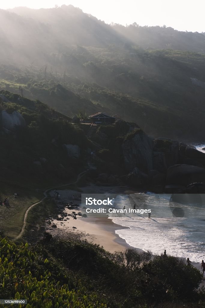 Little beach in a valley at sunset with people standing at the sand Little beach in a valley at sunset with people standing at the sand in Florianópolis, SC, Brazil 12-13 Years Stock Photo