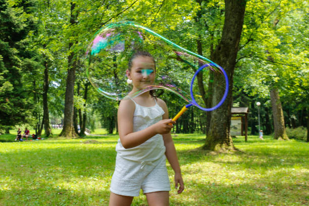 istock Little girl making soap bubbles, Blowing bubbles 1253700124