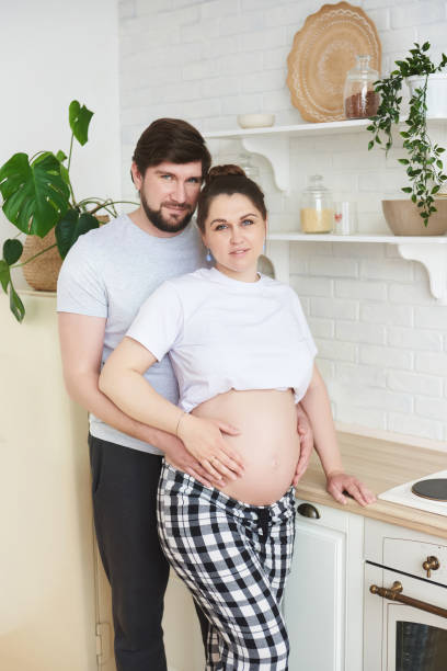 istock Man embracing pregnant wife in kitchen 1253704164