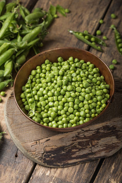 istock Young fresh green peas on wooden  table viewed from above 1253705230