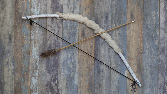 ancient white wooden hunting bow on a wooden background