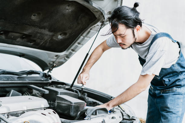 istock Young Asian handsome mechanic in uniform fixing a broken engine at the garage. Repair of machines, fault diagnosis, repair specialist,technical maintenance and people concept. 1253707559