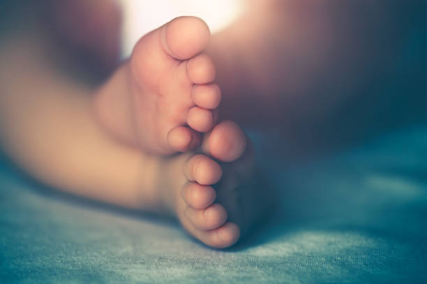 Closeup Photo of a Tiny Bare Feet of Precious Little Baby. Newborn Child Sleeping at Home. New Life Concept.