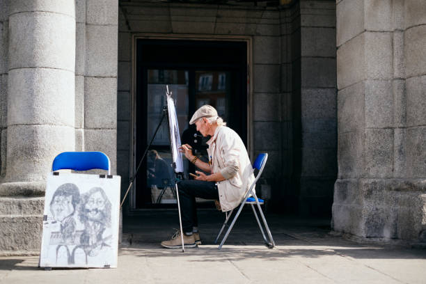 Old Male Street Painter Drawing Portrait Of Tourist Mature Man Working As Street Artist Painter, Drawing Portrait Of Tourist On Canvas In Town Square, Madrid, Spain. caricature photos stock pictures, royalty-free photos & images