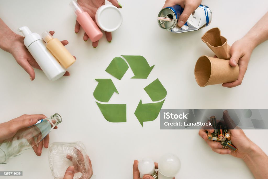 Your life improved. Top view of many hands holding different waste, garbage types with recycling sign made of paper in the center over white background Top view of many hands holding different waste, garbage types with recycling sign made of paper in the center over white background. Sorting, recycling waste concept. Horizontal shot. Top view Recycling Stock Photo