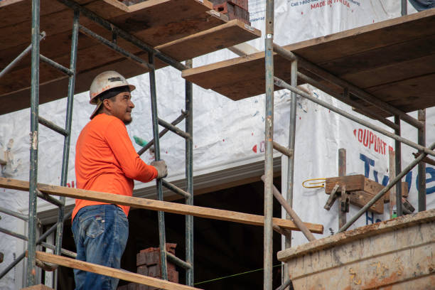 un albañil sobre andamios mira por encima de una instalación de chapa de ladrillo en nueva construcción en atenas, georgia. - mason brick bricklayer installing fotografías e imágenes de stock