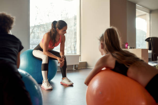 istock Young female trainer explaining something to kids while they are working out with exercise ball in gym. Sport, healthy lifestyle, physical education concept 1253713201
