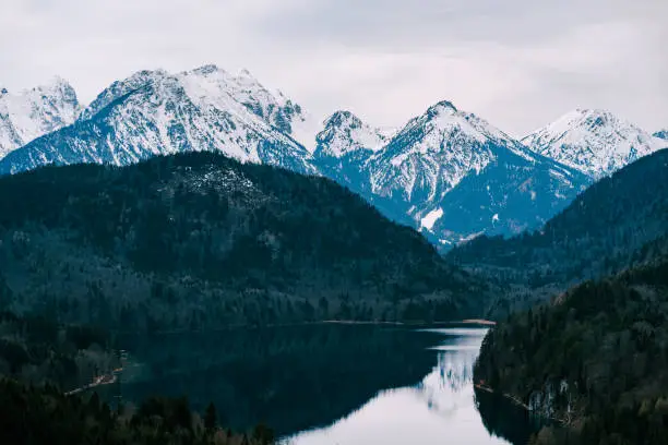 Snow-covered mountains over Lake Alpsee in Germany. High quality photo