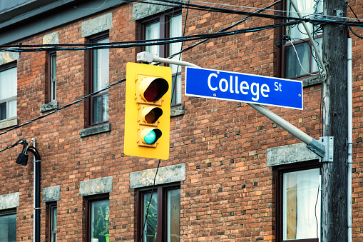 Toronto College street sign with traffic light with a brick wall building in the background.