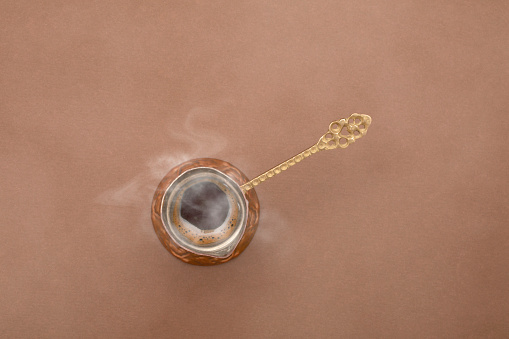 Coffee pot with hot coffee photographed on brown background