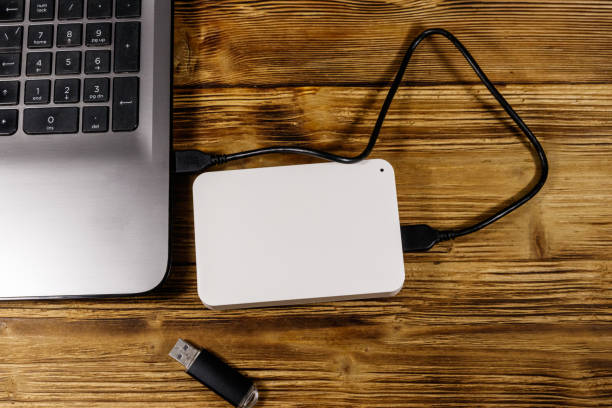 istock External HDD connected to laptop computer and USB flash drive on a wooden desk. Top view. Concept of data storage 1253718278