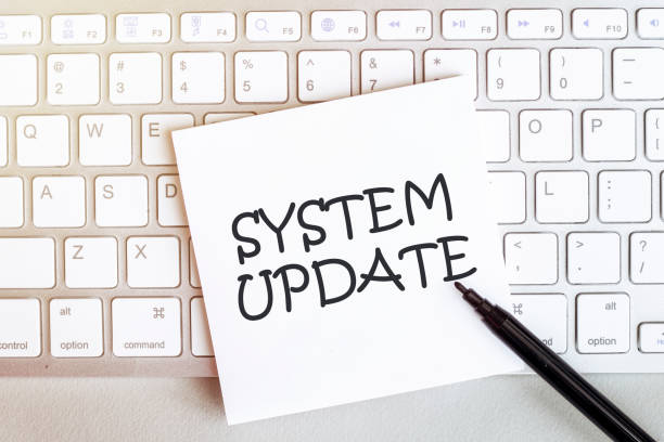 istock piece of paper with text SYSTEM UPDATE on the keyboard on a white background with a black felt-tip pen 1253723067