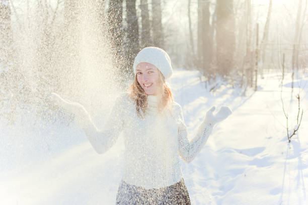Sun and snow weather, woman throws snow, winter season and nature beauty, winter white clothes