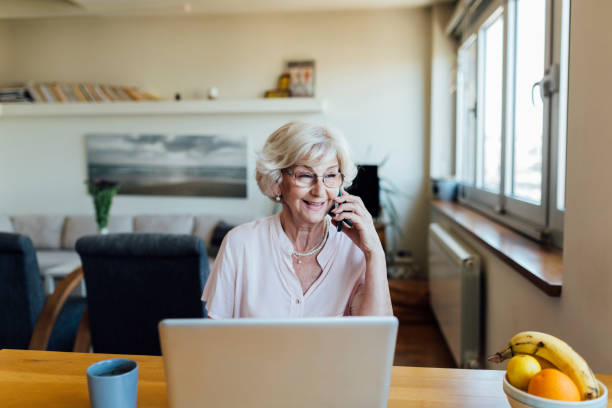 istock Senior woman using a laptop and a smart phone at home 1253726877