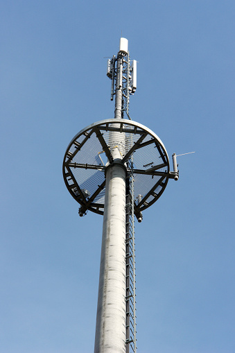 Top of a cell tower with maintenance platform. Blue sky.