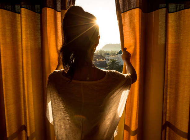 giovane donna stare nella stanza tenda aperta vedendo la bella alba - hotel war foto e immagini stock