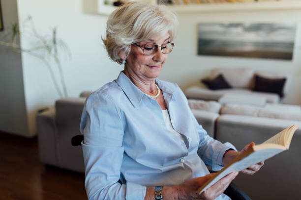 istock Elderly woman reading a book at home 1253729726
