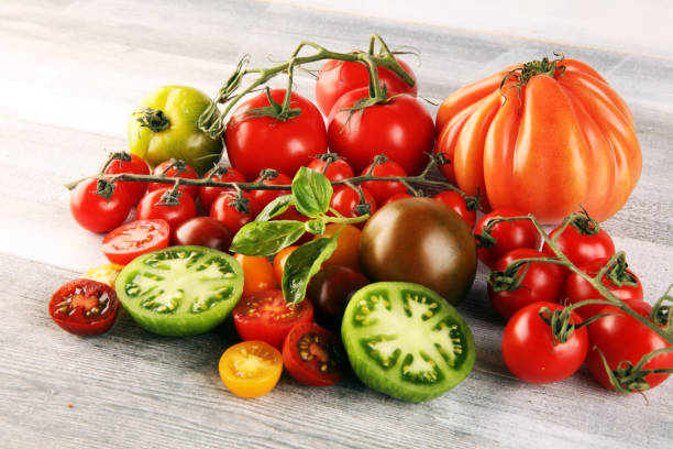 istock various colorful tomatoes and basil leaves on rustic table. 1253730517
