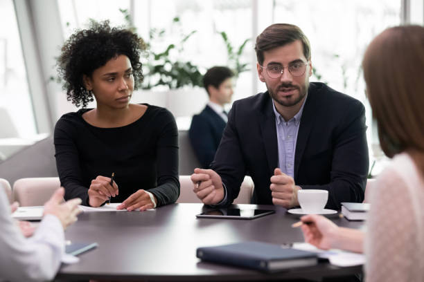 istock Millennial business man speaking to diverse team training brainstorming meeting 1253731521