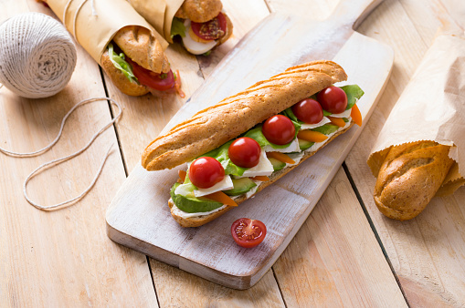 Fresh submarine sandwiches with varieties of fillings on wooden background