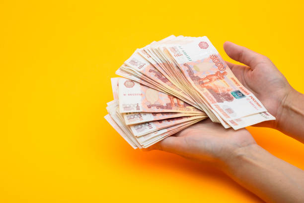 istock On the palms are five thousandth bills, yellow background 1253733648
