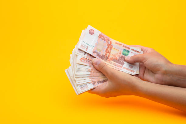 istock In hands lies a bundle of five thousandth bills on a yellow background 1253733673