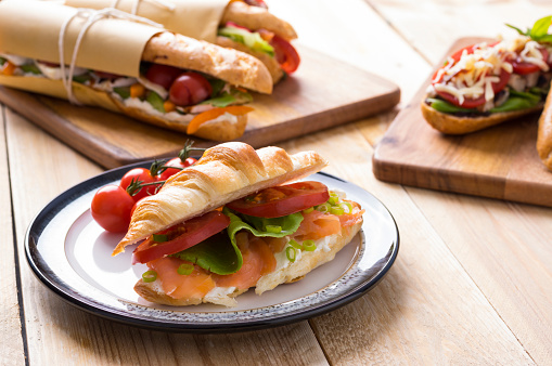 Fresh submarine sandwiches with varieties of fillings on wooden background