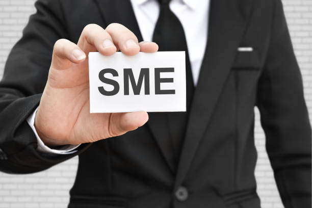 istock Man hand holding paper card with word SME 1253739267