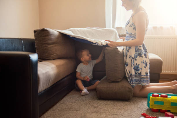 istock Devoted mother making hideout  for her toddler boy on a floor of a living room, using sofa cushions 1253739572
