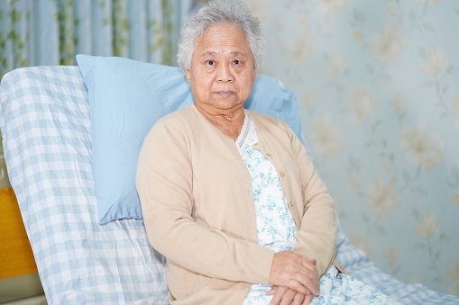 Asian senior or elderly old lady woman patient smile bright face while sitting on bed in nursing hospital ward, healthy strong medical concept.