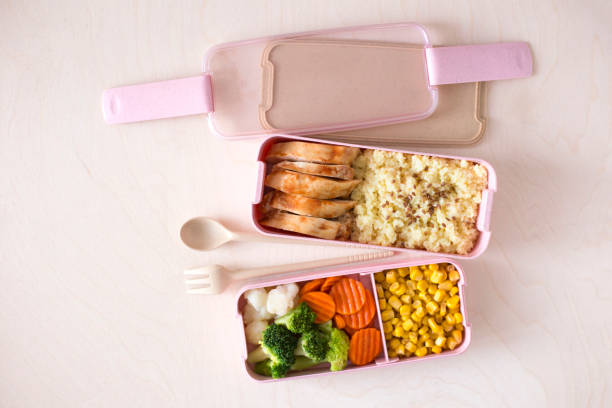 istock Office lunch boxes made of biodegradable plastic with chicken, porridge, fresh vegetables on light wooden background 1253741631