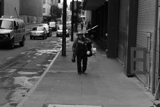 MEXICO CITY, MEXICO - September / 21 / 2018 Homeless old man walks through the streets of the city of Mexico at noon accompanied by his violin with which he plays traditional Mexican music to get money