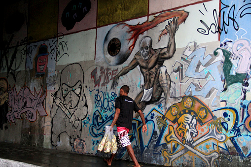 salvador, bahia / brazil - september 10, 2014: person is seen passing by the wall painted with graphite drawings in the city center of Salvador.\