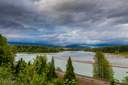 Looking upstream on the Skeena River towards Terrace, beside the CN Railway Line, on a cloudy summer evening, in British Columbia, Canada.