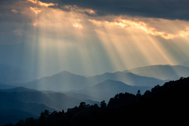 istock Ray of sunlight shining through clouds to mountains. 1253761844