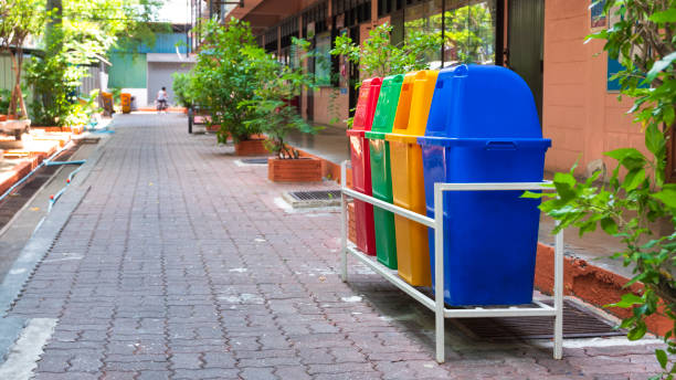 Perspective and side view of multicolored garbage bins on brick pavement in the school