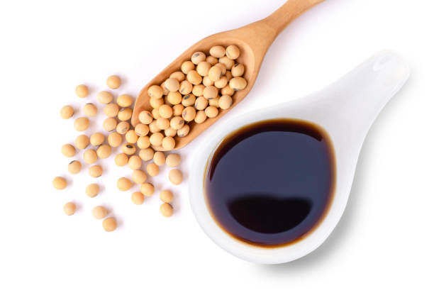 Soy bean Tasty soy sauce in white ceramic bowl with soy beans in wooden scoop  isolated on white background. Top view. Flat lay. soy sauce photos stock pictures, royalty-free photos & images