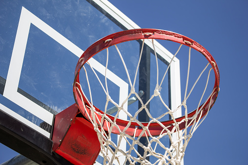 A low angle closeup of a basketball backboard, hoop and net