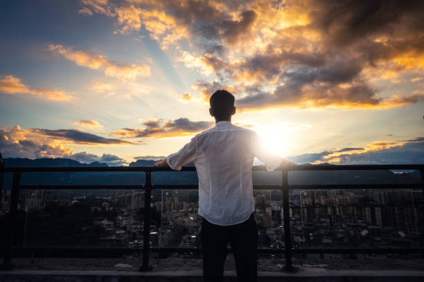 istock Young man watching the city sunset on the rooftop 1253791163