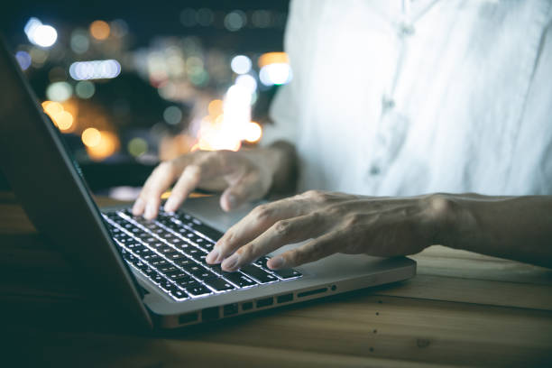 istock Man hand using laptop with city night background 1253791182